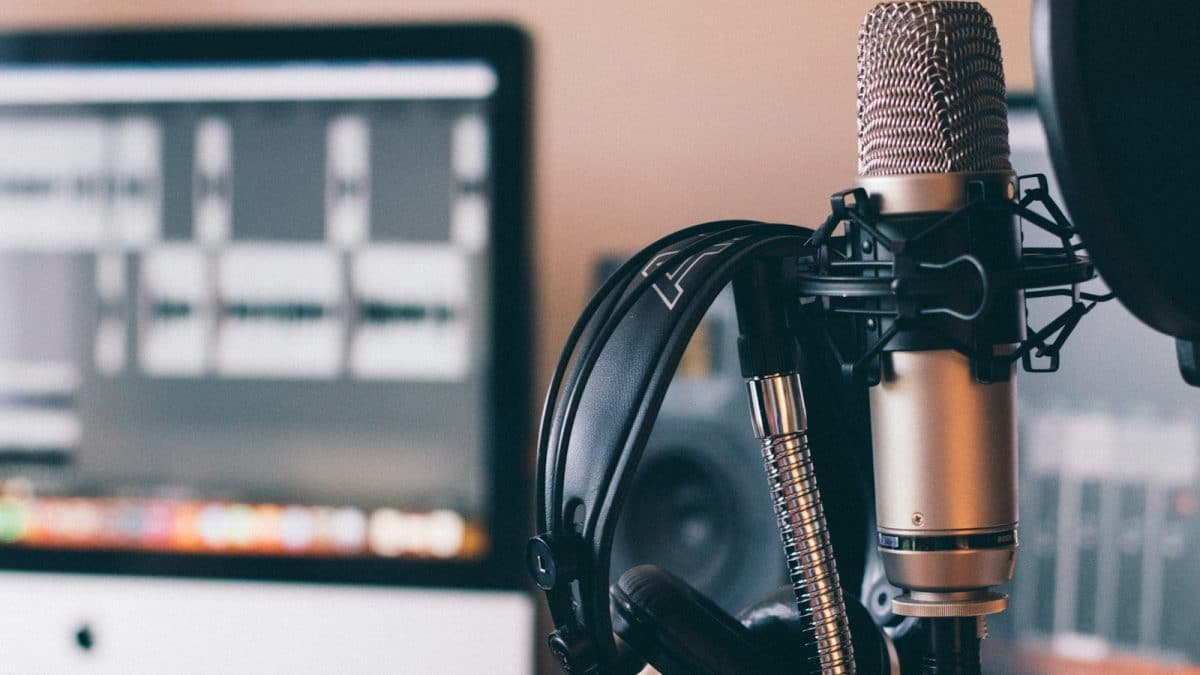 Micrófono de condensador con unos audifonos colgados, en un estudio de podcast