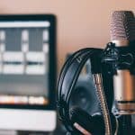 Micrófono de condensador con unos audifonos colgados, en un estudio de podcast